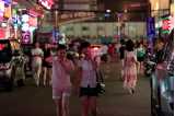 Två unga asiatiska kvinnor  iklädda shorts och sommarblusar promenerar på en gata.