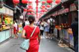 En bild på en kvinna som går längs en kinesisk marknad.