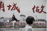 Folkmyller på en gata i Shanghai med reklamskyltar i bakgrunden.