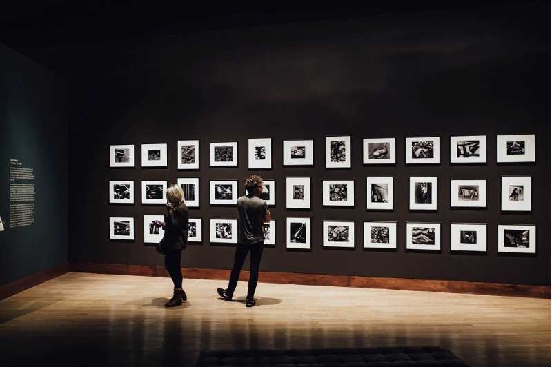 Två personer står framför en vägg med fotografier