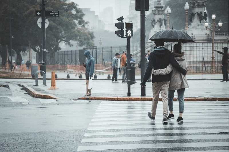 Ett par korsar en gata i regnet